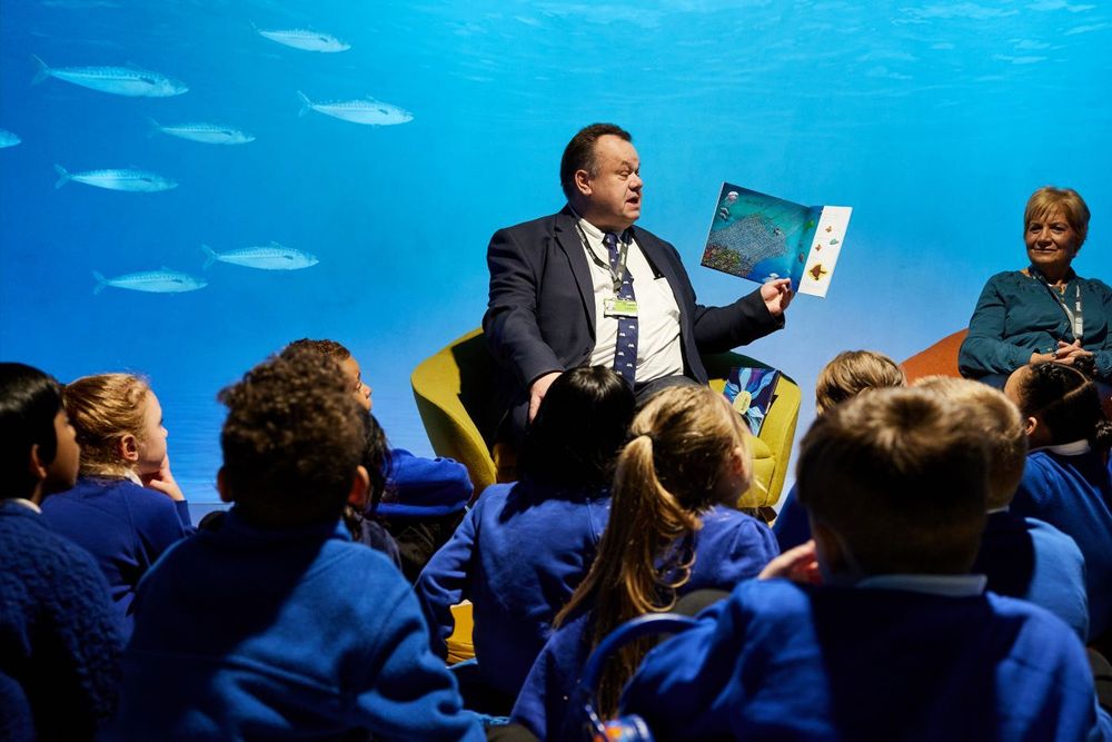 A member of library staff reads a story to a group of schoolchildren.