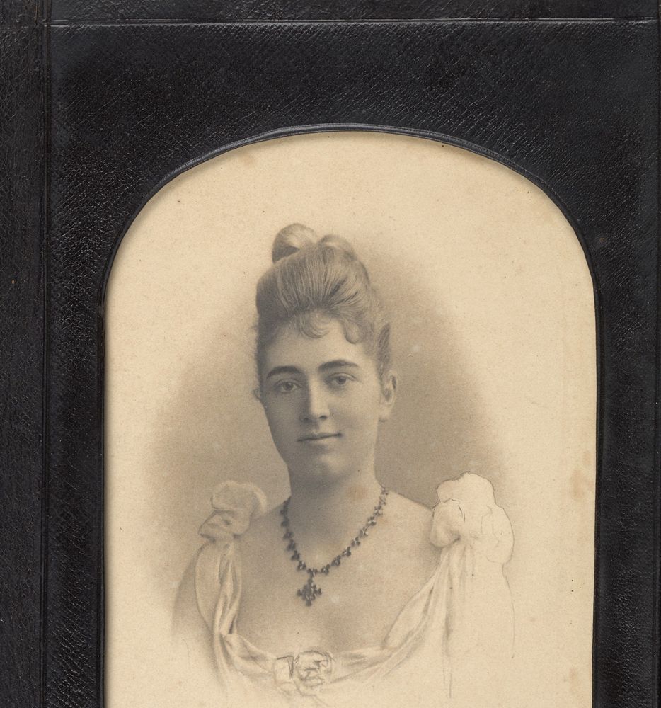 Sepia portrait of a young woman in a formal dress with her hair up, wearing a necklace.